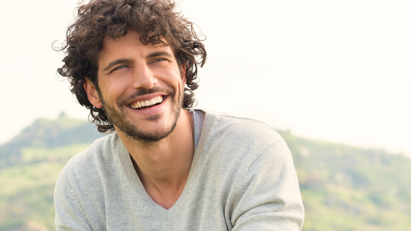 Smiling man with curly hair outdoors