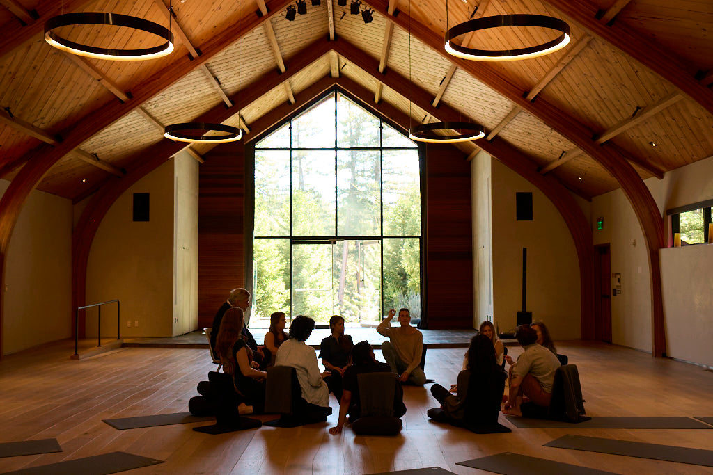 A small group gathered in circle inside a stunning timber-framed retreat hall